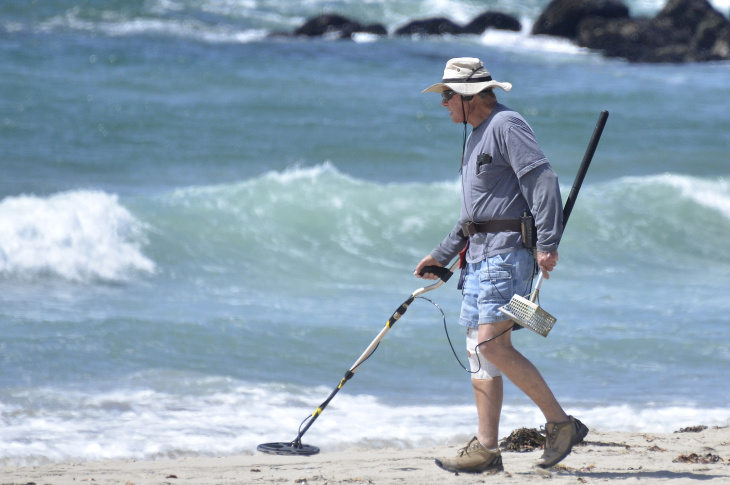 A man uses a metal detector while search