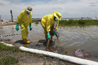 Workers are seen as they use a vacuum hose to capture some of the oil washing on to Fourchon Beach from the Deepwater Horizon oil spill in the Gulf of Mexico on June 28, 2010 in Port Fourchon, Louisiana.