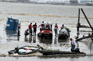 Oil cleanup workers salvage their equipment after water, pushed by high seas, inundated their oil boom containment staging area on July 7, 2010 in Grand Isle, Louisiana.