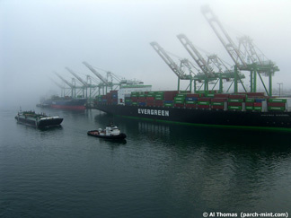 A tugboat pulls a barge through the Port of Los Angeles on a foggy morning.