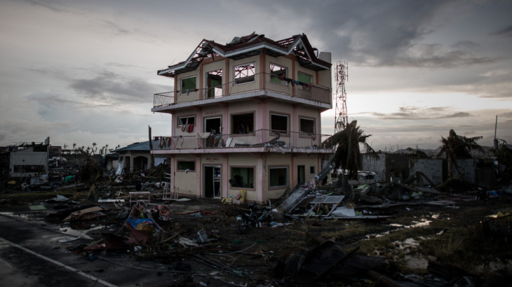 The sun sets behind a house damaged by Typhoon Haiyan outside the hard-hit city of Tacloban. The Philippines has gotten better at preparing for typhoons, but remains extremely vulnerable.