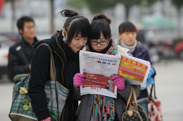 Chinese students look at a newspaper out