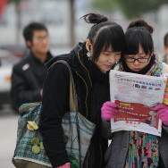 Chinese students look at a newspaper out