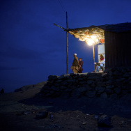 Afghans look on from a lit hut at dusk i