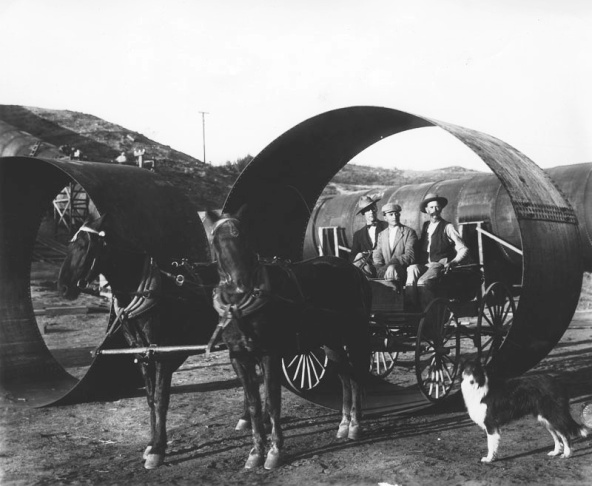Construction of the Owens Valley Aqueduct. A horse-drawn carriage poses in one of the large pipes used in the construction of the aqueduct.