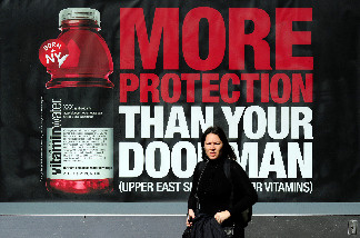 A woman walks by an advertisment for a vitamin water soft drink in New York, March 8, 2010.