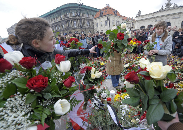 People carry flowers in front of the Presidential Palace in Warsaw on April 10, 2010, as they gather to pay tribute after the crash of the Presidential plane in Smolensk. A plane carrying Polish president Lech Kaczynski and much of the country's military and state elite crashed in thick fog in Russia on Saturday killing all 96 people on board in a blazing inferno.