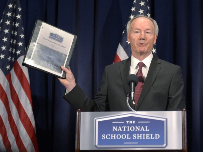 Former Republican Congressman Asa Hutchinson holds up his task force's report during a news conference Tuesday in Washington, D.C.