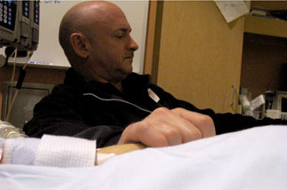 Mark Kelly holding the hand of his wife, Rep. Gabrielle Giffords, in her room at University Medical Center in Tucson on Sunday, Jan. 9, 2010.