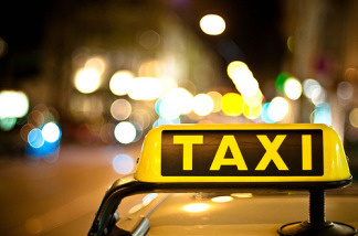 Taxi cab driving on a street at night.