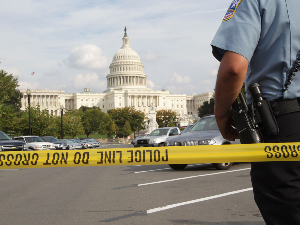 An officer stands just outside police tape Thursday as authorities investigate a car chase that began at the White House and ended near the Capitol.