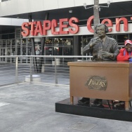 Darrell Bailey, known as Clipper Darrell, sits with the Chick Hearn statue in the Staples Center courtyard