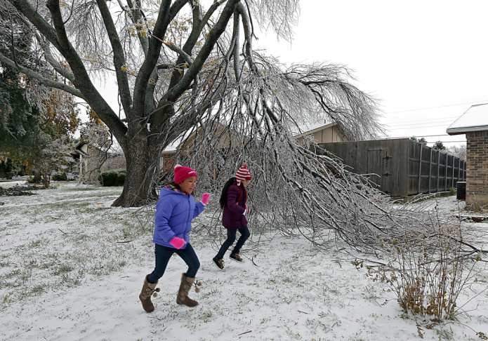 Enari Hernandez, left, 6, and her cousin Maritza Jimenez, 6, play in front of a damaged tree in their neighbors yard on Saturday in Plano, Texas.