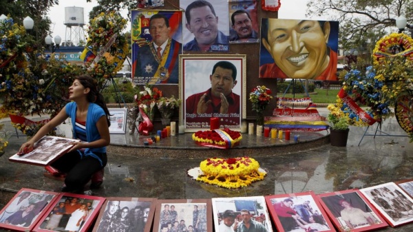 A woman wipes photos of late President Hugo Chavez at a makeshift altar for him in the main square of Sabaneta, western Venezuela, on Saturday.