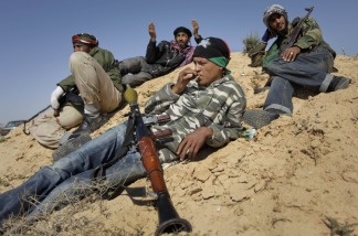 Rebel fighters rest on sand dunes near the front line in Brega, Libya, on April 4, 2011.