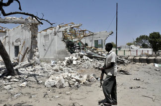 File photo: A government fighter walks by destroyed building after a suicide car bomb ripped through a police base in Mogadishu on February 21, 2011 killing nine people after a weekend of bloody fighting between pro-government forces and Al Qaeda-inspired insurgents.