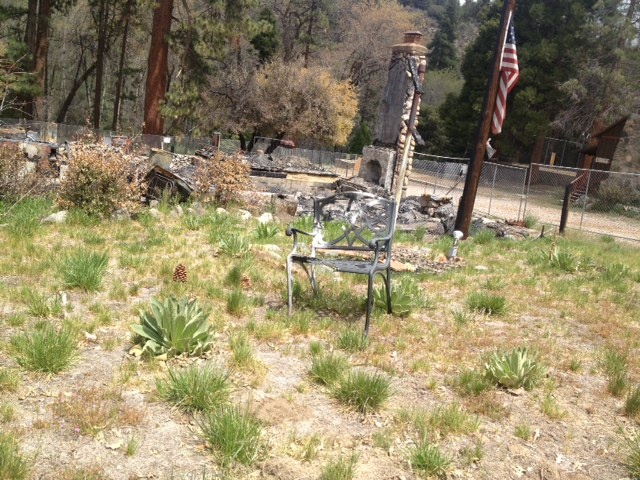 An American flag flies half-staff in the middle of the cabin grounds where Christopher Dorner died near Big Bear. Many items, like furniture and books, have stayed put after the fire burned the walls of the cabin down to its foundation.