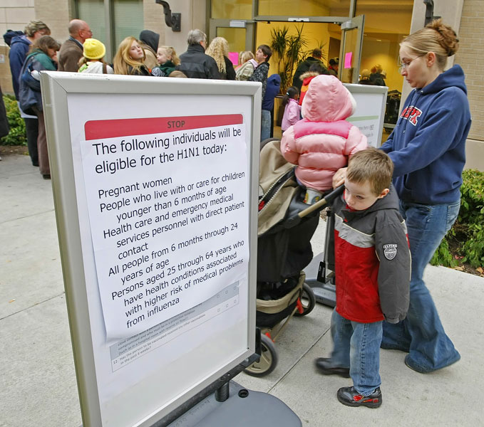 A young boy looks at a sign as he and his mother arrive to wait in line with several thousand other people at the Utah County Health Department to get H1N1 vaccine shots October 27, 2009 in Provo, Utah. After health department got a shipment of 4000 vaccines overnight, a large line formed with a wait of four to five hours.