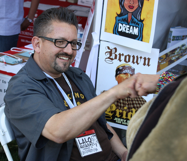 Lalo Alcaraz, creator of the first nationally-syndicated, politically-themed Latino daily comic strip, “La Cucaracha”, greets a fan at his booth.