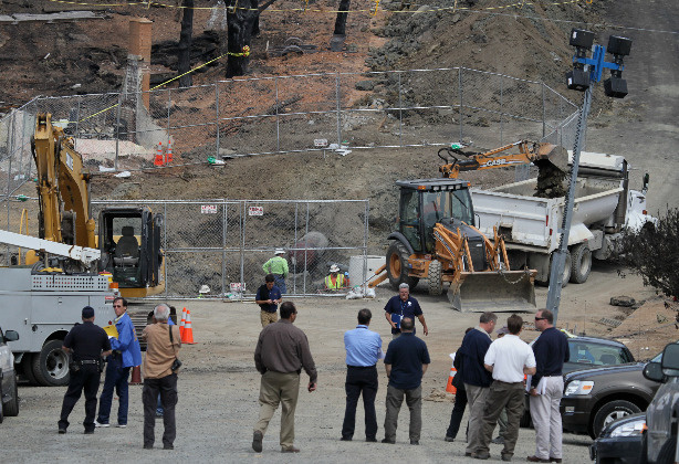 Officials look on as Pacific Gas & Electric workers excavate the crater at the epicenter of a deadly gas main explosion September 13, 2010 in San Bruno, California. State regulators have ordered Pacific Gas & Electric to inspect all of their gas lines following a deadly blast that destroyed thirty eight homes, severely damaged dozens more and killed at least four people in a San Bruno, California neighborhood near San Francisco International Airport on Thursday evening.
