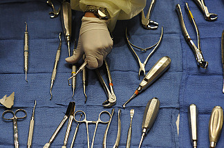 A healthcare professional reaches for a tool when caring for a patient.