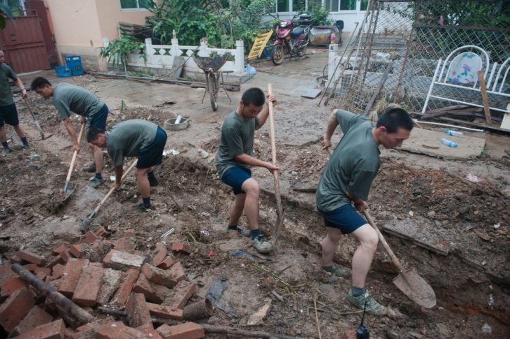 Workers help clear mud from a street in