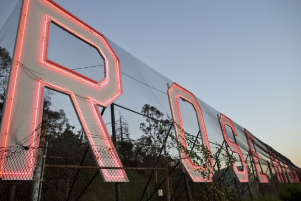 Photo: The Rose Hills cemetery's famed neon sign, just lit up as the sun starts to set. Credit: Maya Sugarman/KPCC