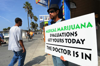 A man holds a placard advertising medical marijuana outside an evaluation clinic on Venice Beach in Los Angeles on October 9, 2009.