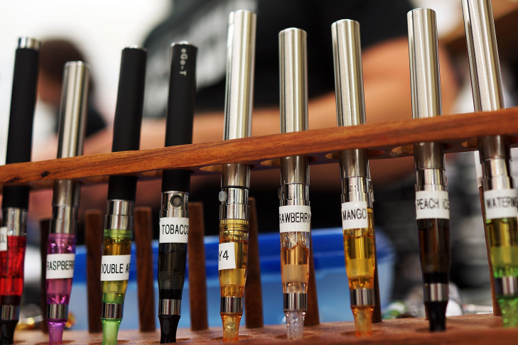 A variety of .electronic cigarette flavors are viewed for sale at Vape New York. Electronic cigarettes, or e-cigarettes, are battery powered devices that vaporizes a nicotine laced liquid solution into an aerosol mist which simulates the act of tobacco s