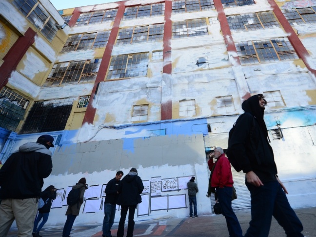 People walk in front of New York's graffiti iconic spot "5Pointz," after the building was painted white in New York.