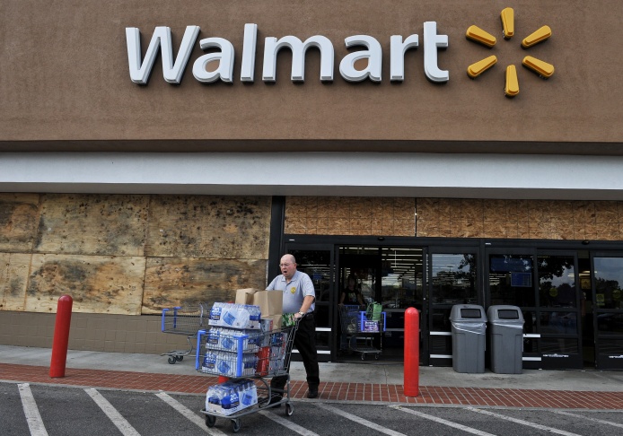A man walks out of a boarded up Walmart