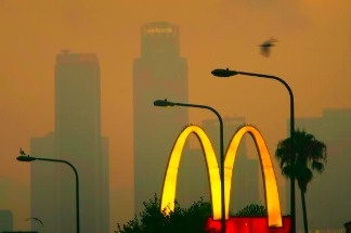 A McDonald's fast-food restaurant sign glows above the city skyline located in the Figueroa Corridor area of South Los Angeles, Los Angeles, California.