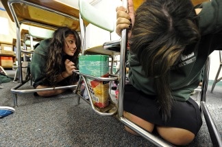 Two girls take cover beneath desks during The Great California ShakeOut, an annual earthquake drill, on Oct. 21, 2010 at Providence High School in Burbank.