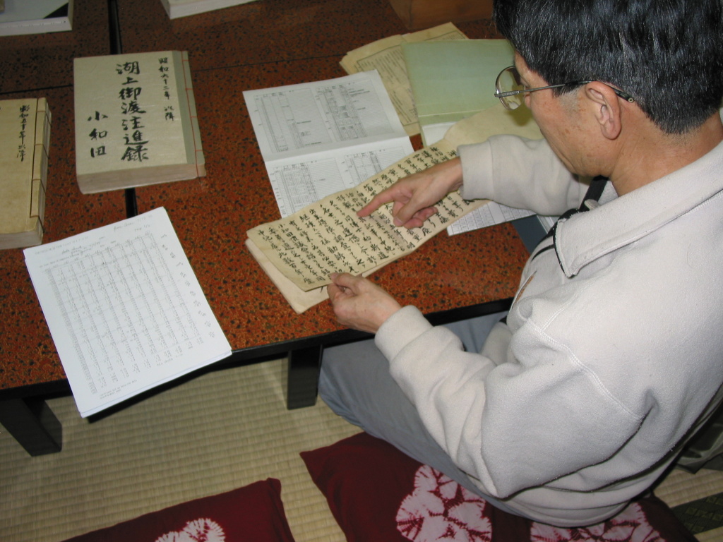 The Priest Mr. Kiyoshi Miyasaka pointing out some of the records on lake ice and the omiwatari. His data sheet summarizing the records are on the table. Taken Nov. 3, 2005. The Priest Mr. Kiyoshi Miyasaka pointing out some of the records on lake ice and the omiwatari. His data sheet summarizing the records are on the table. Taken Nov. 3, 2005.