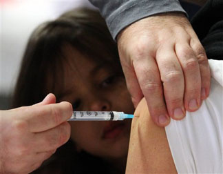 Four-year-old Rowan Watchmaker looks on as her mother is injected with the H1N1 flu vaccine at a clinic in Ottawa, Monday, Oct. 26, 2009.