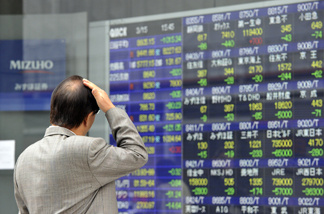 A pedestrian gazes at a share prices board in Tokyo on March 15, 2011.