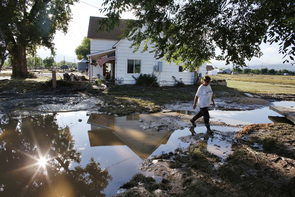 CORRECTION Colorado Flooding Local resident Sue Sadar walks across a trench of mud which used to be a lawn as she and family members clean property in an area inundated in flooding, in Hygiene, in Boulder County, Colo., Monday Sept. 16, 2013. Searches continue for missing people in isolated Colorado mountain towns.