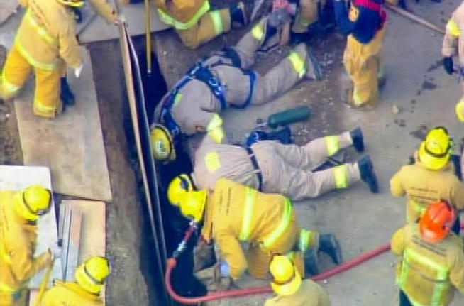 Rescuers attempted to retrieve a worker trapped in an 8-foot-deep trench on North Benedict Canyon Drive.