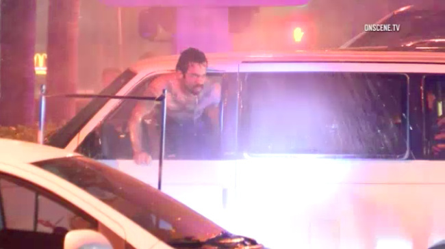 A man sticks he head out of a minivan he was driving in Orange after police blasted the car with a fire hose on March 12, 2017. Police said the man appeared to pour gasoline on a cloth and lit a cigarette. He was fatally shot after he pulled a knife, police said.