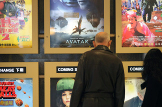 Mercer 2268 A man stands before posters advertising films including 'Avatar', in Hong kong on December 28, 2009.