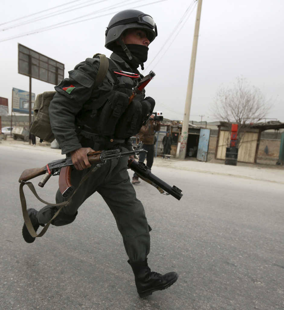 An Afghan security officer runs toward the scene of Friday's bombing in Kabul. Three NATO personnel were killed and at least six Afghan civilians were wounded.
