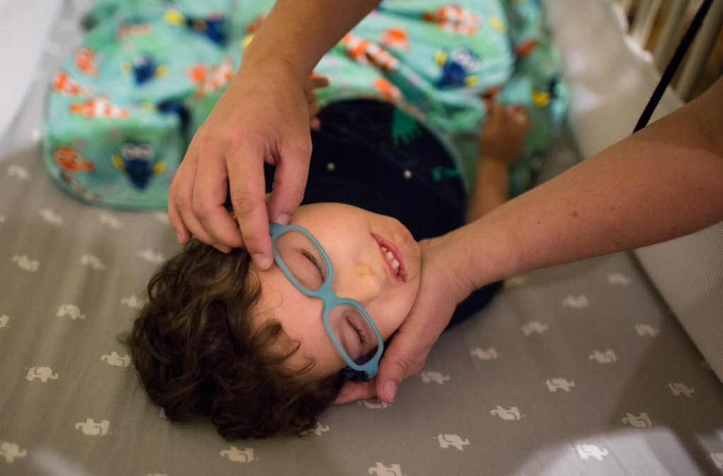 Kathleen helps her son Gideon get his glasses on. Part of Gideon's brain was damaged during development, which effects his vision.