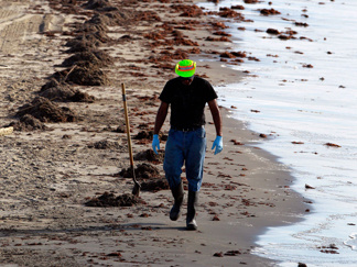 A worker cleans up oil from the Deepwater Horizon spill along the beach Sunday in Grand Isle, La.