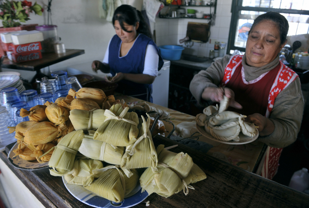 Tamales (ground maize with meat wrapped Tamales are displayed in a bar as women prepare empanadas in Salta, at the foothills of the Andes mountain range, in the Argentine northern province of Salta, on June 14, 2009.