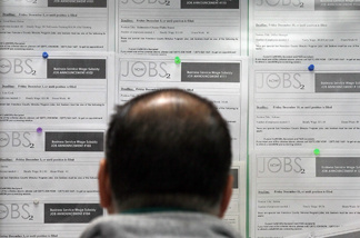 A job seeker looks at listings on a bulletin board.