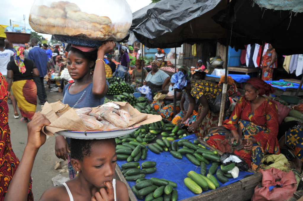 ICOAST-RELIGION-ISLAM-RAMADAN People carry fish and loaves of bread on their heads as a woman sells cucumbers in the market of Abobo, near Abidjan, Ivory Coast, on July 9, 2013, the first day of the Muslim holy month of Ramadan.