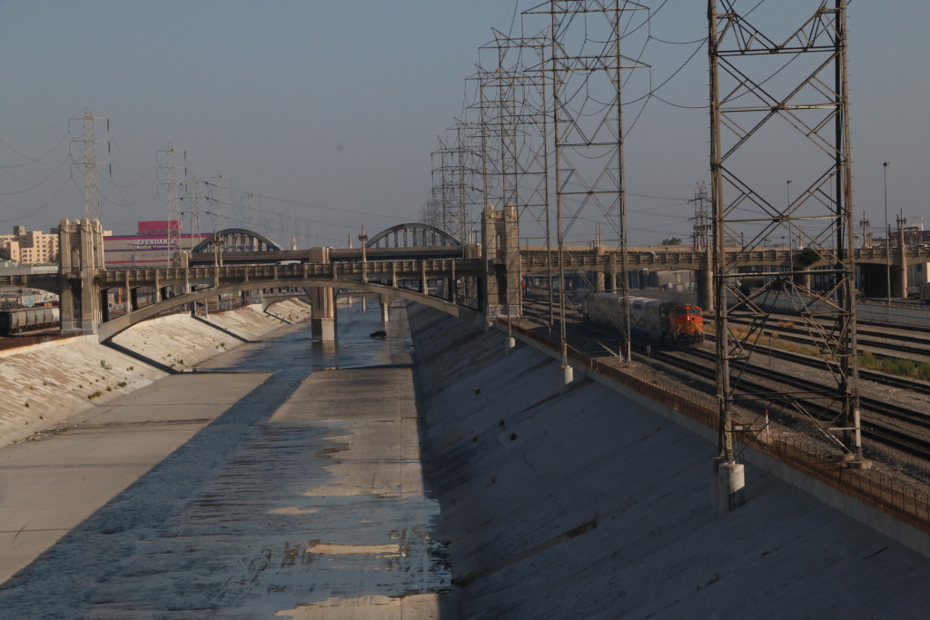 LA River concrete View of the Los Angeles River encased in concrete surrounded by railroad tracks and factories in downtown.