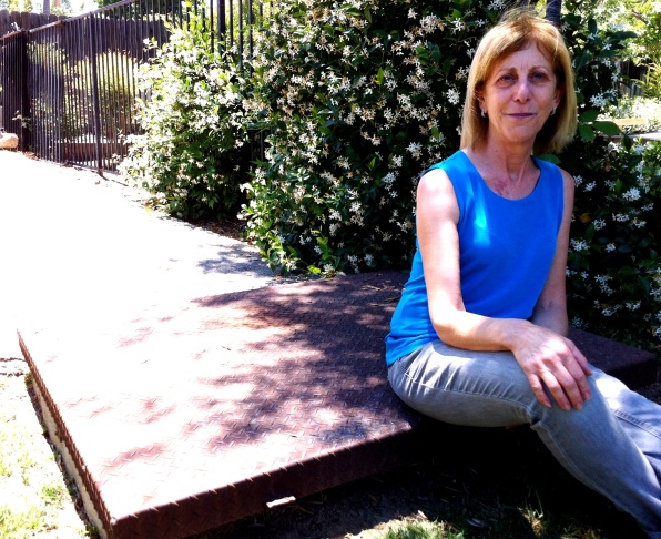 Deb Kaufman sits on the lid of the fallout shelter her dad, nuclear engineer Alvin B. Kaufman, built in their back yard in Woodland Hills.