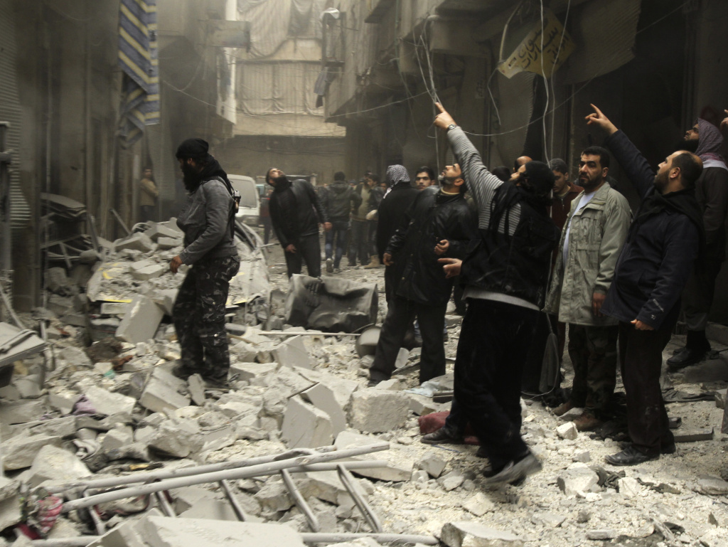 Syrian look up after an apparent airstrike by forces loyal to President Bashar Assad in Aleppo, Syria, on Monday. A new report, released Monday, alleges "systematic" torture and killing by the Assad regime.