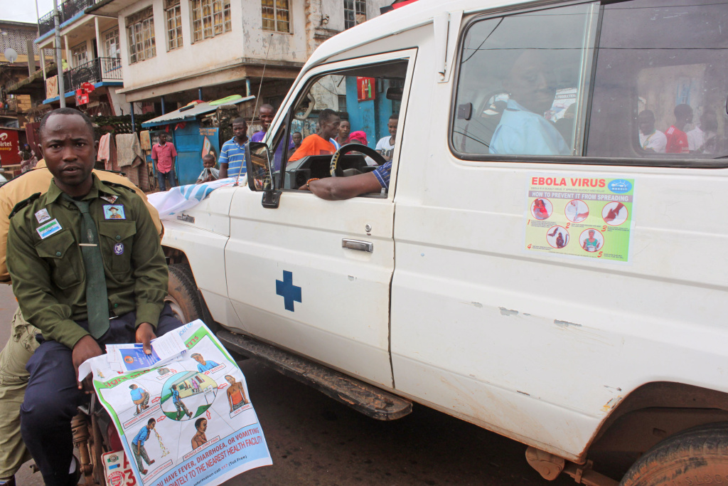 Sierra Leone West Africa Ebola In this photo taken on Monday, Aug. 4, 2014, health workers, left, traveling by motorbike with others inside a truck, right, as they attempt to educate people about the deadly Ebola virus in the city of Freetown, Sierra Leone. The global Ebola outbreak touched American shores more definitively Monday, as Atlanta awaited the arrival of its second Ebola patient by morning, and a New York hospital announced it had isolated a man with possible symptoms who walked into its emergency room.(AP Photo/ Youssouf Bah)